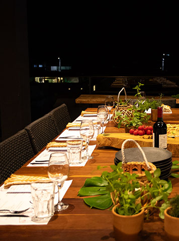 Mesa de jantar preparada para evento gastronômico com taças e ingredientes frescos
