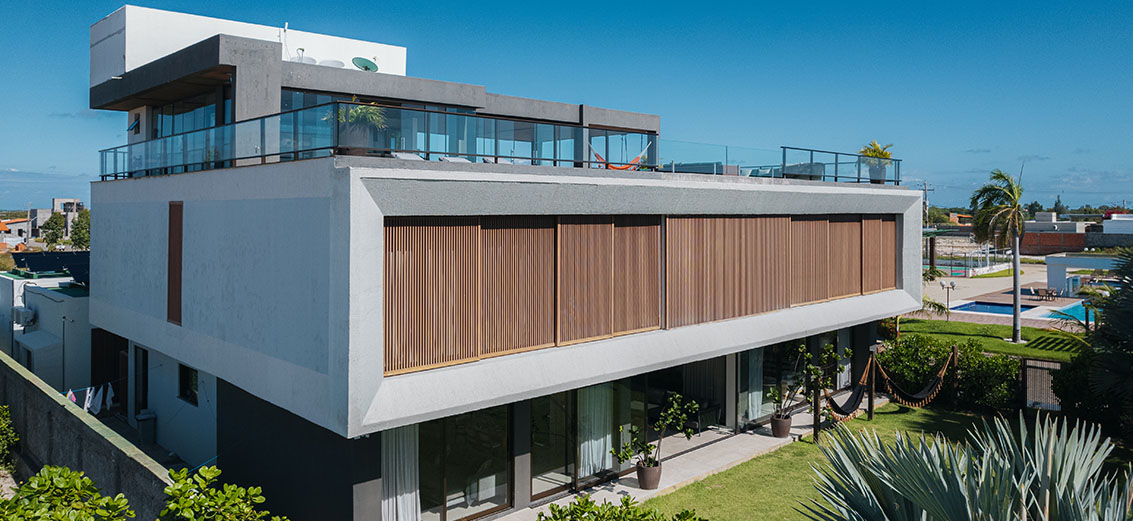 Vista aérea da fachada da Casa Lençis com rooftop, brises de madeira e jardim