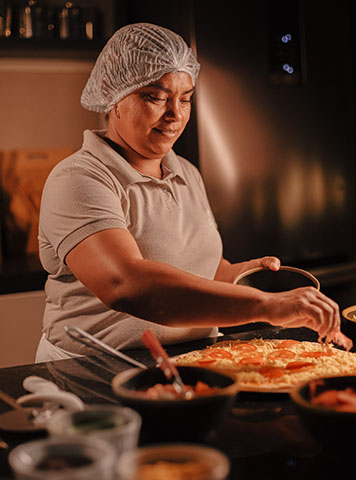 Cozinheira preparando pizzas artesanais na cozinha da Casa Lençóis