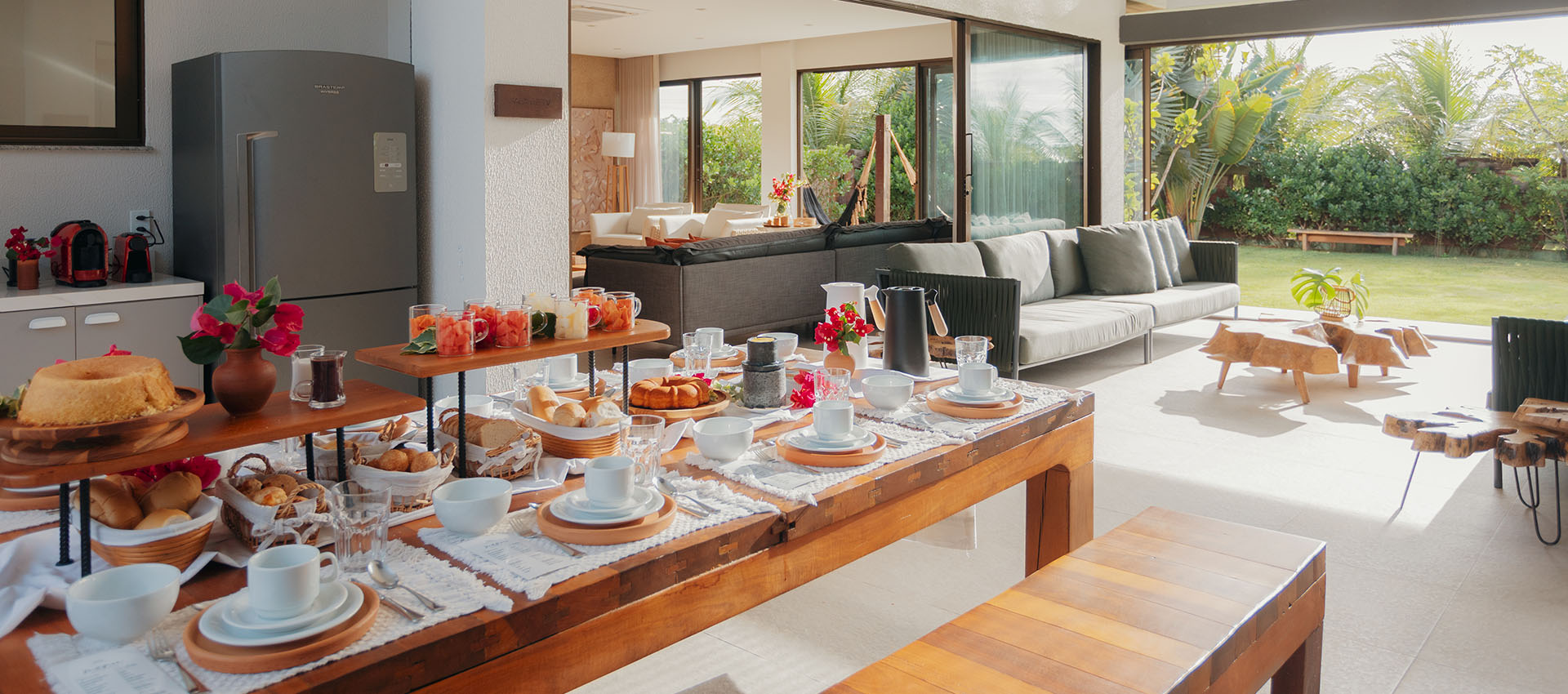 Mesa de café da manhã com pães, bolos e frutas na cozinha integrada