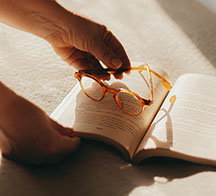 Livro aberto com óculos de leitura sob a luz do sol