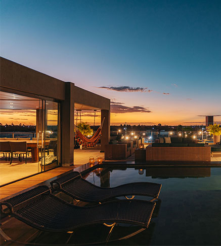 Rooftop da Casa Lençóis ao entardecer com piscina, espreguiçadeiras e rede