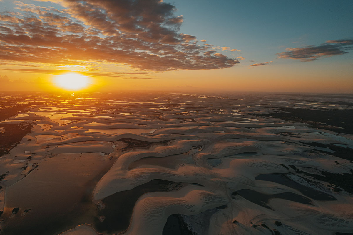 Vista aérea dos Lençóis Maranhenses ao pôr do sol com dunas e lagoas